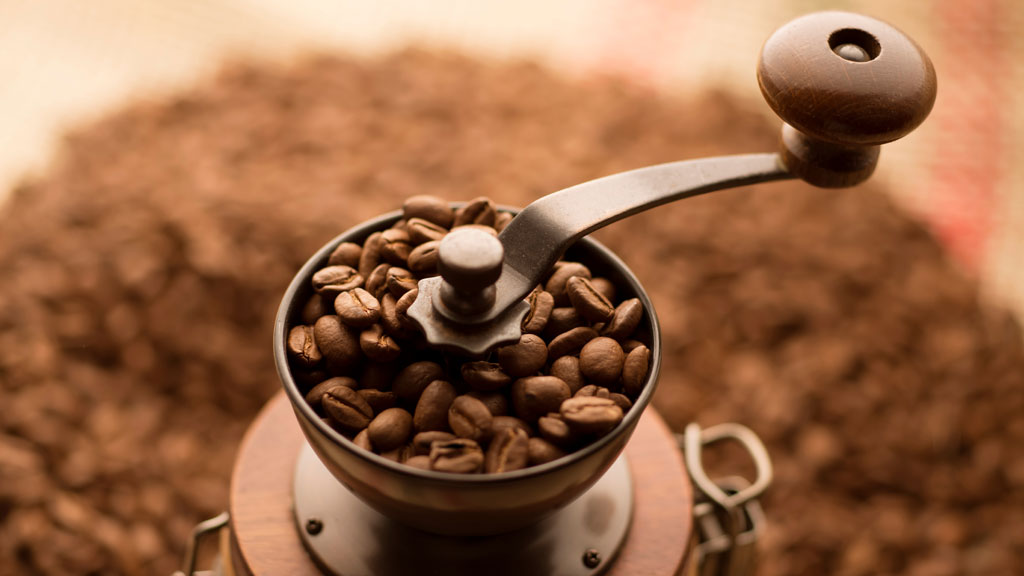 Moulin à café manuel avec grains décaféinés visibles sur plan de travail cuisine française