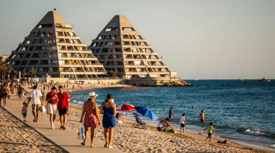 Vue du front de mer de La Grande-Motte avec ses immeubles pyramidaux emblématiques et des vacanciers sur la plage