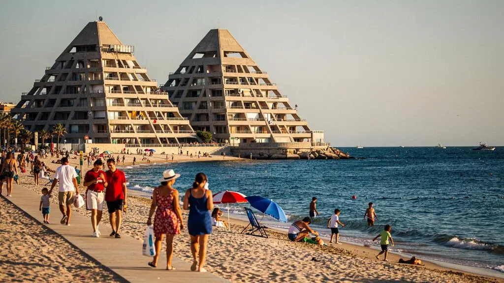 Vue du front de mer de La Grande-Motte avec ses immeubles pyramidaux emblématiques et des vacanciers sur la plage