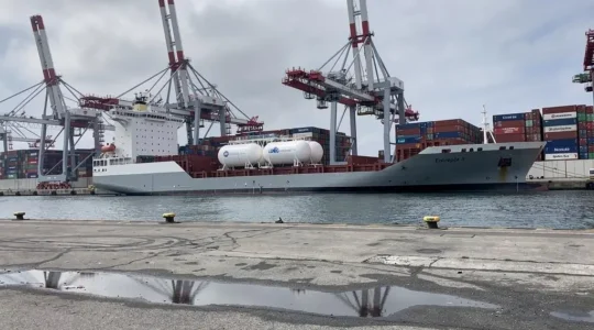 Navire cargo moderne équipé de systèmes de propulsion alternative amarré dans un port industriel français, avec infrastructures portuaires et grues de chargement en arrière-plan